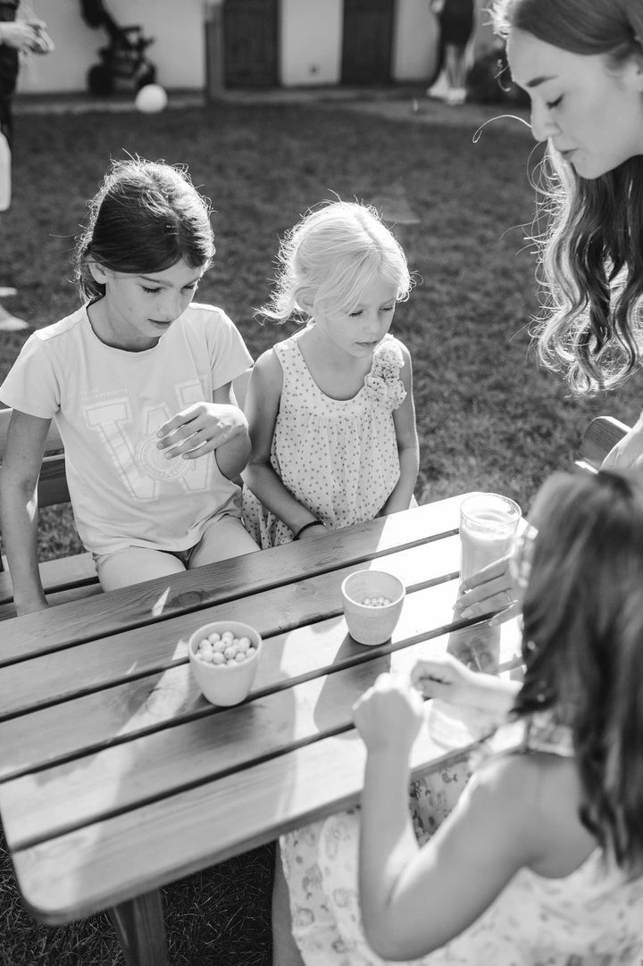 Chůva s dvěma dívkami u stolku na zahradě, černobílá fotografie