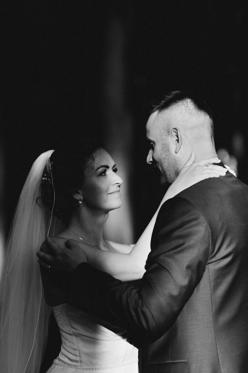 Nevěsta a ženich v objetí během prvního tance, černobílá fotografie